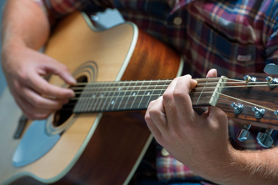 Closeup of man playing acoustic guitar