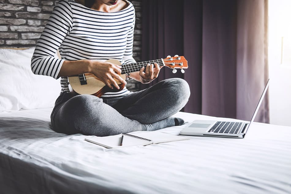 Woman on bed learning ukulele
