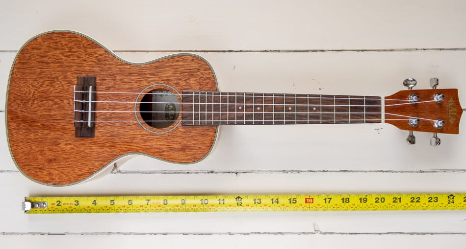 Concert ukulele with measuring tape beside it
